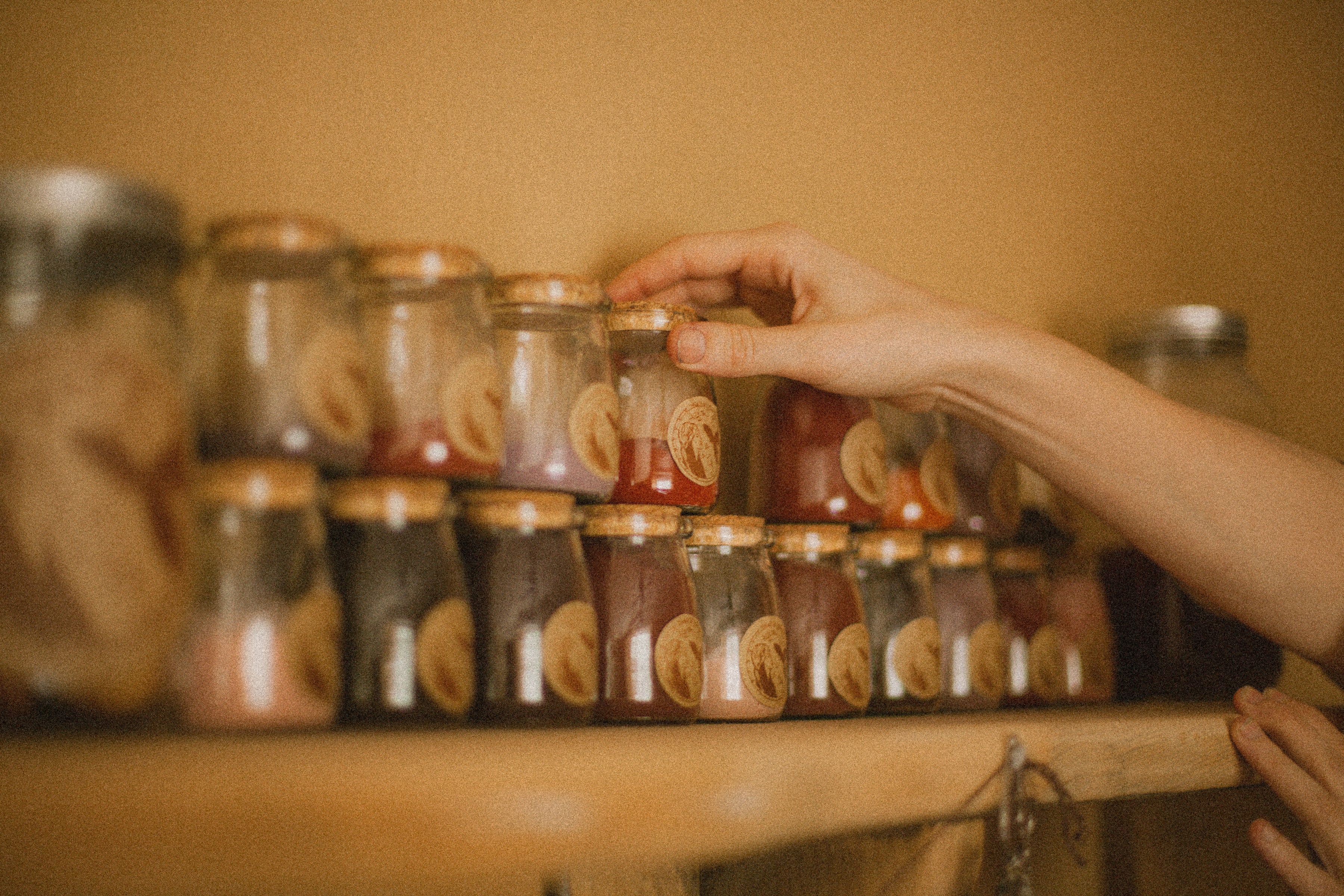 womans hand placing low impact dye jars on the shelf work in studio