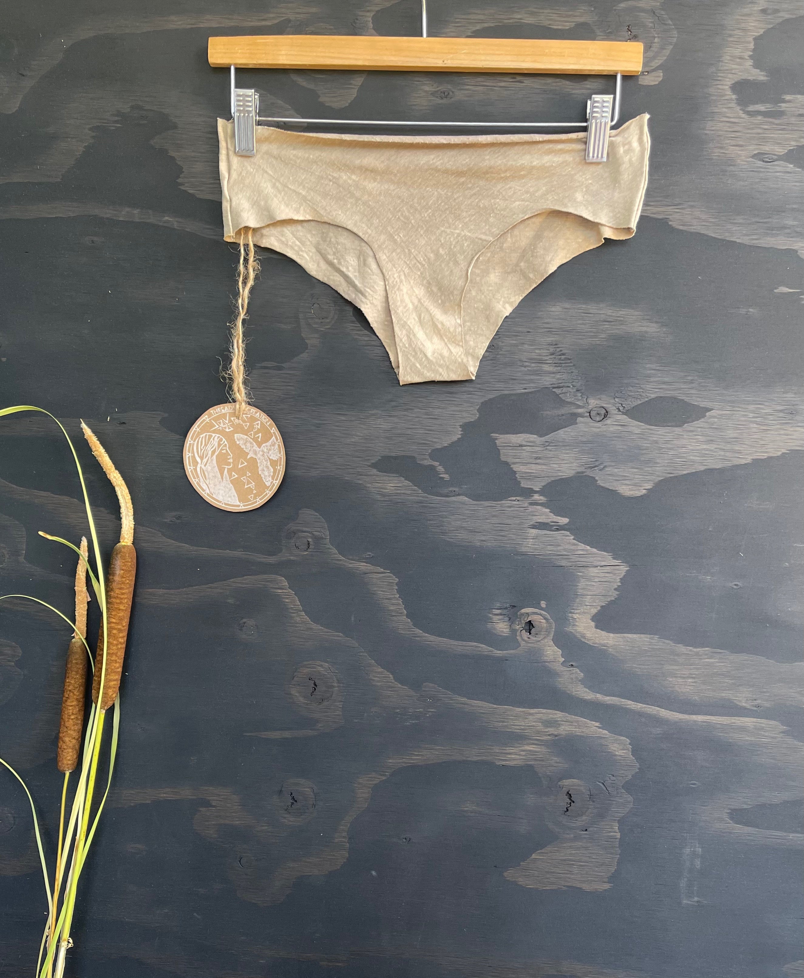hemp panties in sage color on a wooden hanger against a dark background