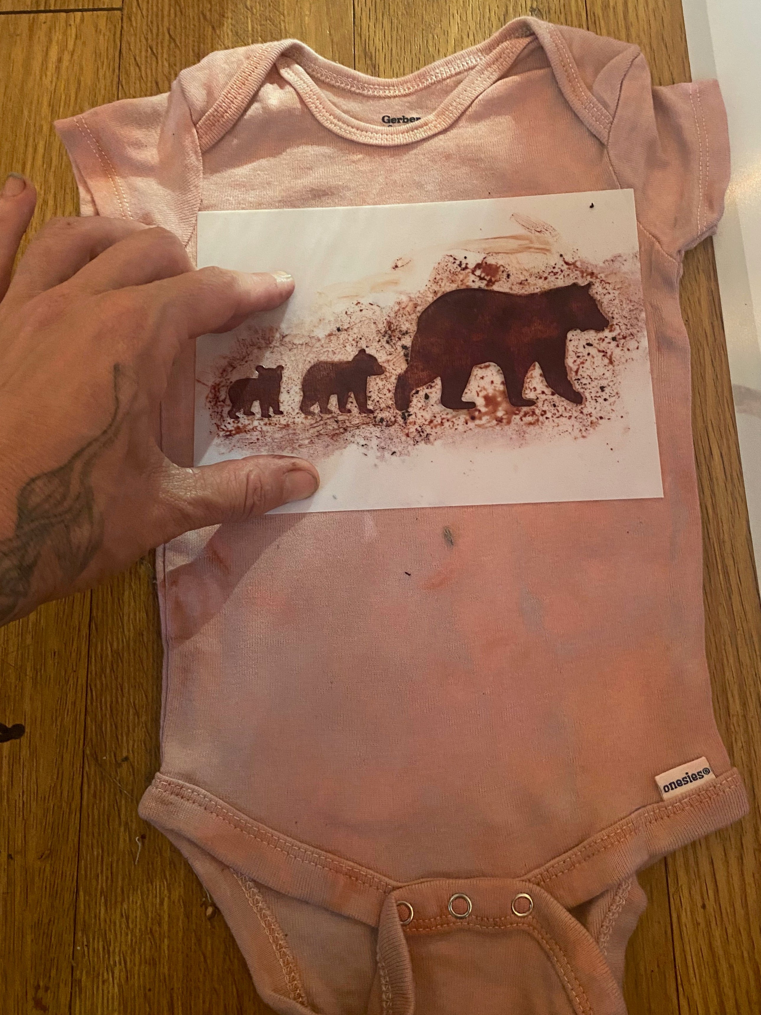 Pink baby onesie with bear design on a wooden surface
