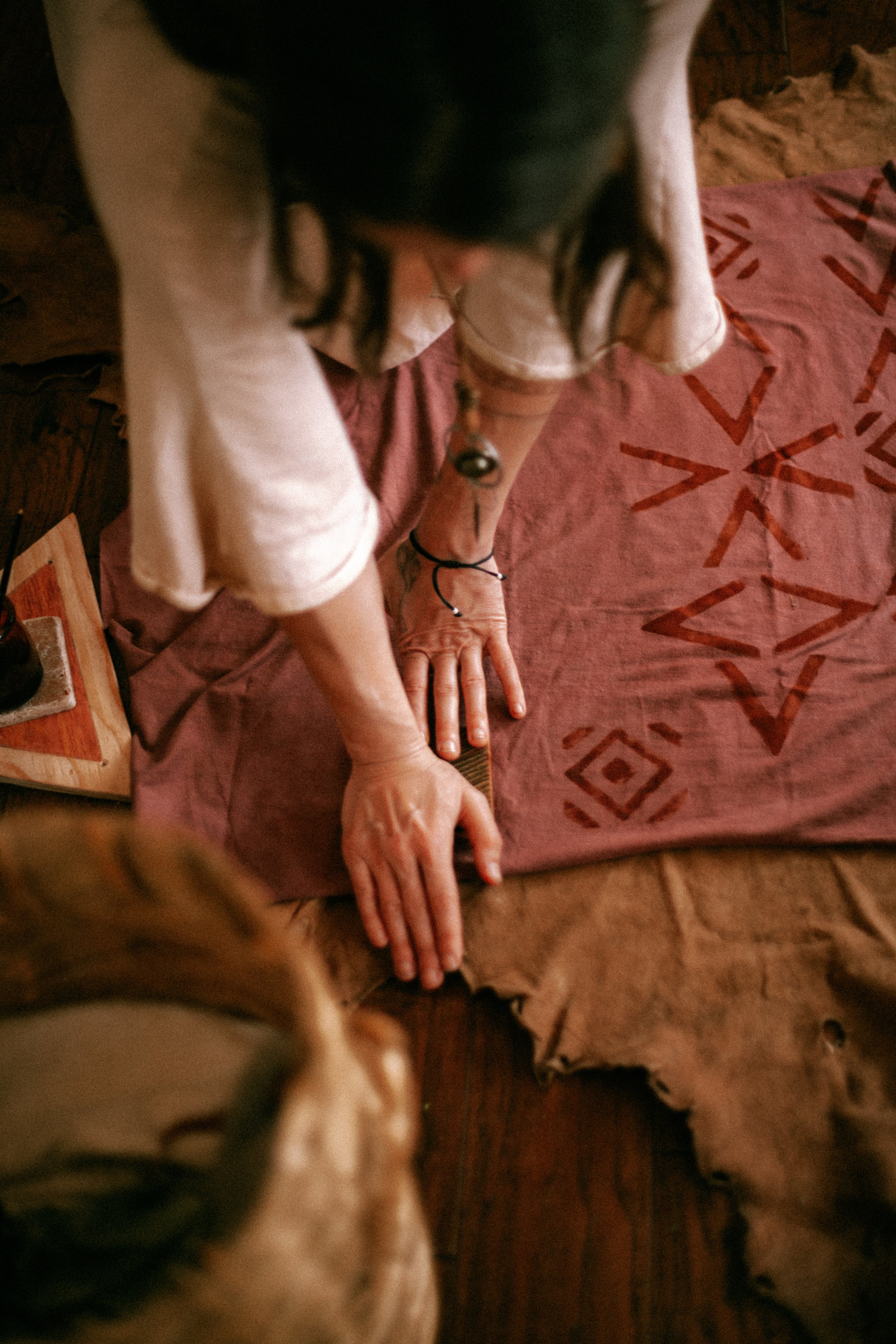 view from above of a woman block printing on pink fabric