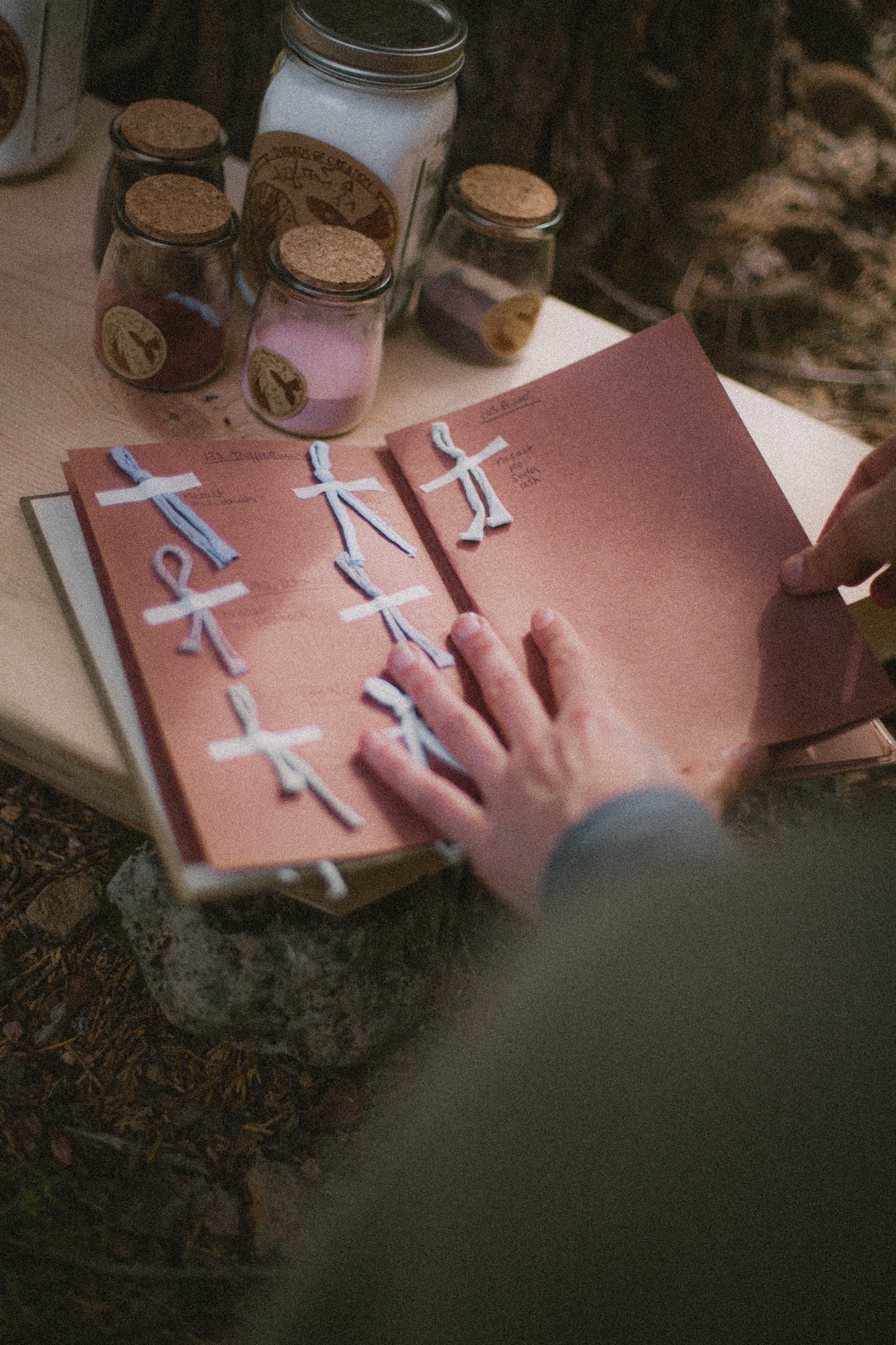 log book of fabric dyes with dye swatches and jars of dye on a wooden table outside