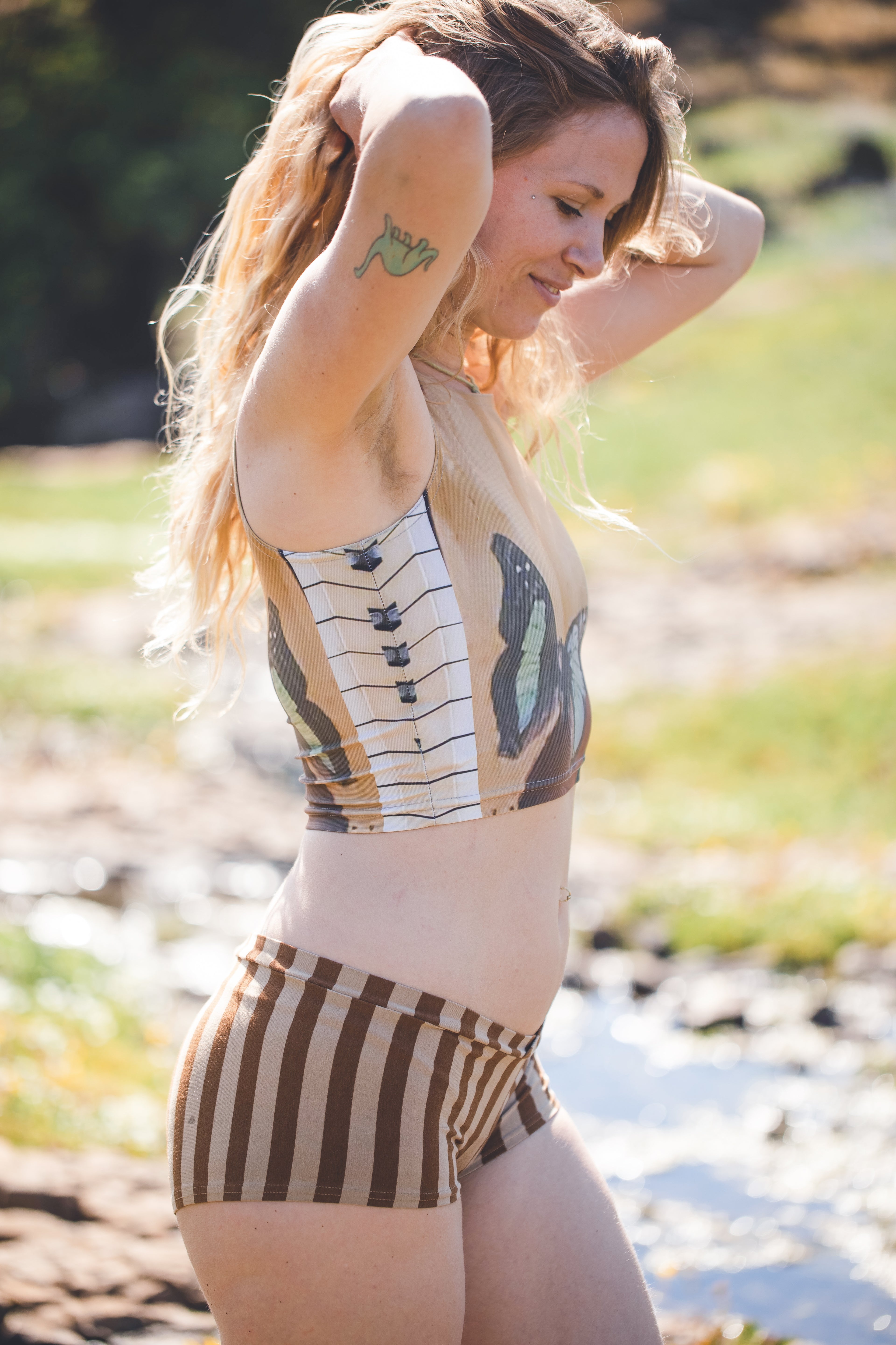 model wearing Yoga top with butterfly and piano painted onto wood in shades of brown and blue