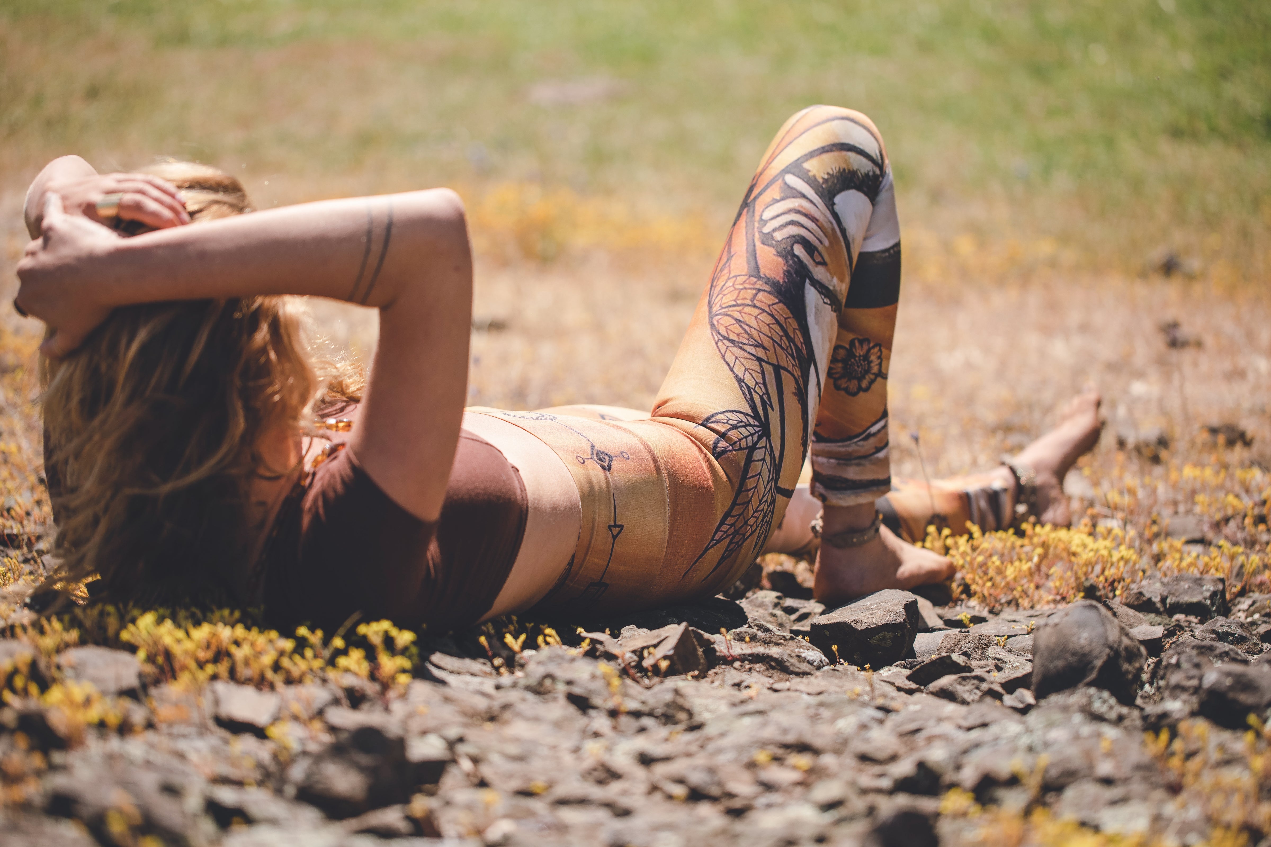 yoga leggings with a floral leaf line and crescent moon designs on a golden brown background.