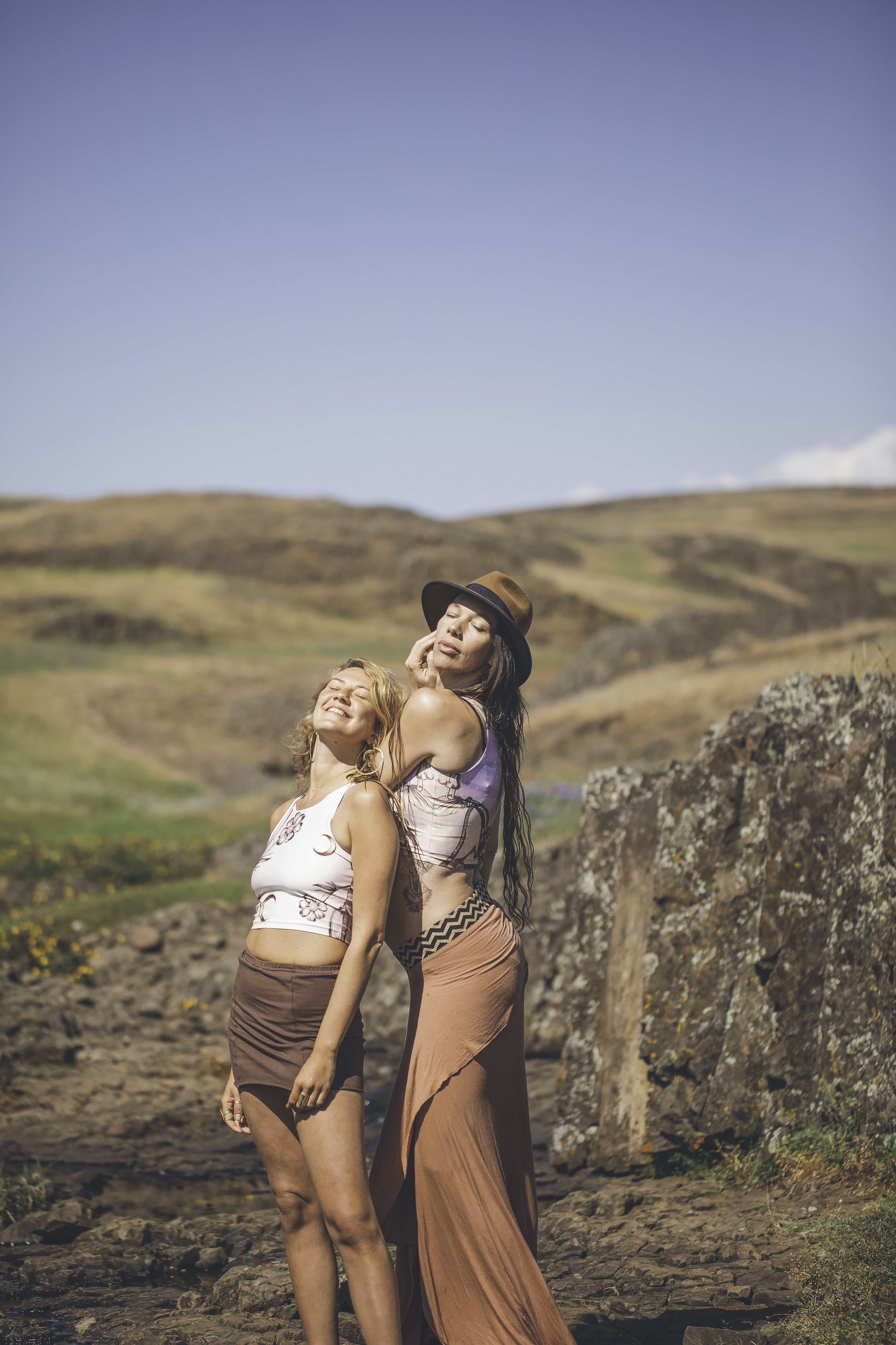 two women in skirts standing in valley wearing Yoga tops in shades of cream and white with a black drawing of a flower and a crescent moon on it