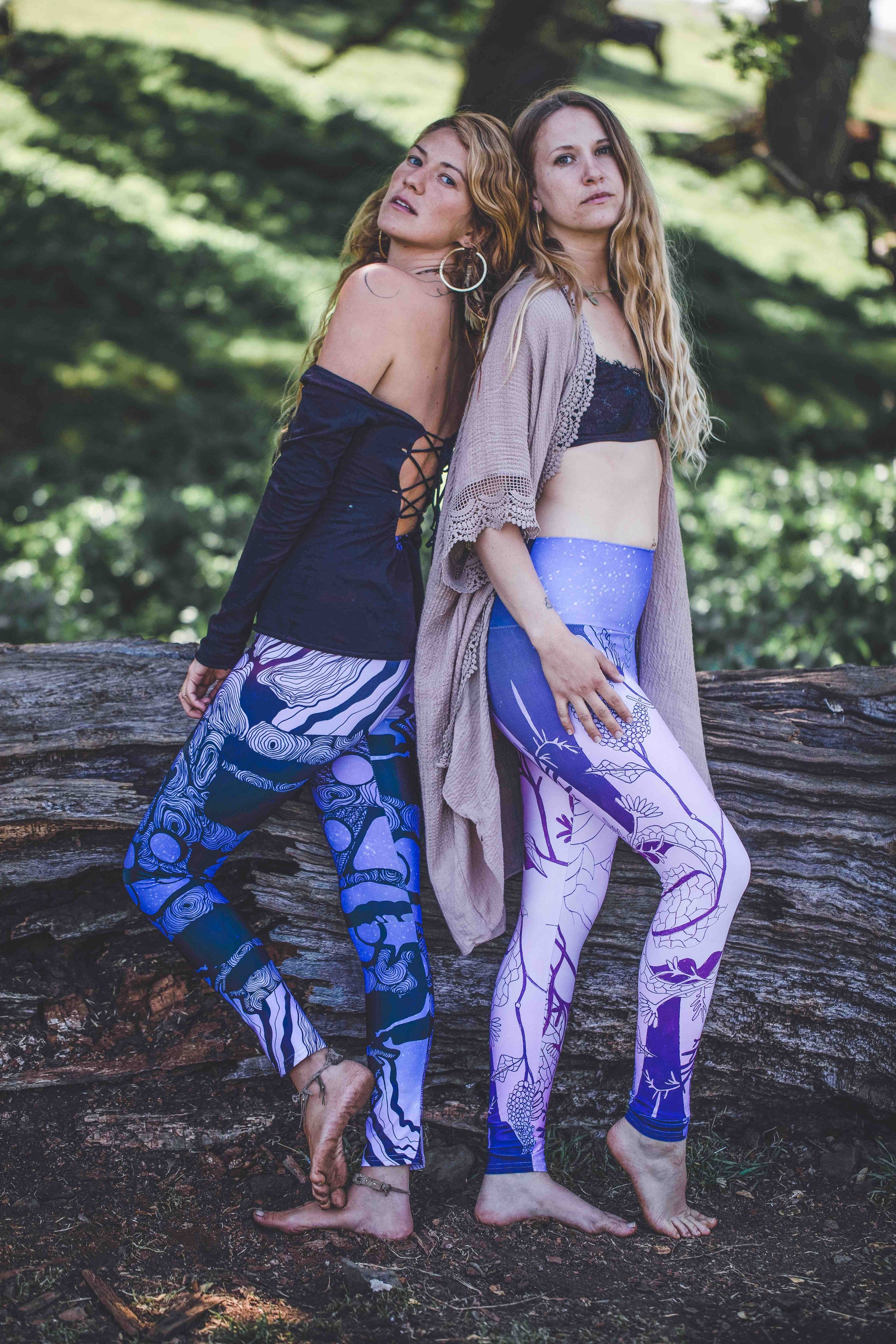 2 women wearing Yoga leggings in blue and purple with black line in the shape of a tree a woman and moons on them