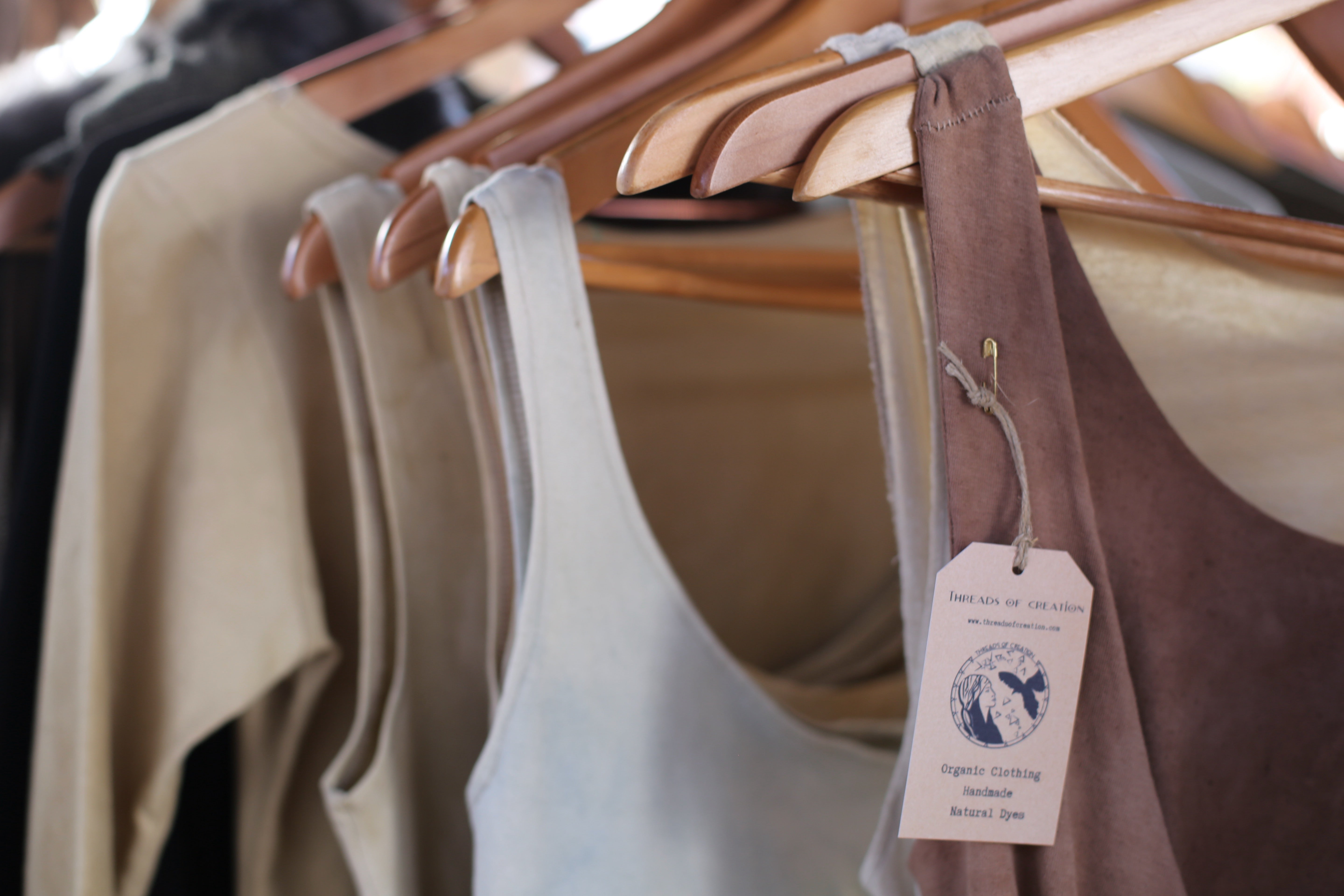 front view f rack o dresses in natural tones and hanging tag for threads of creation