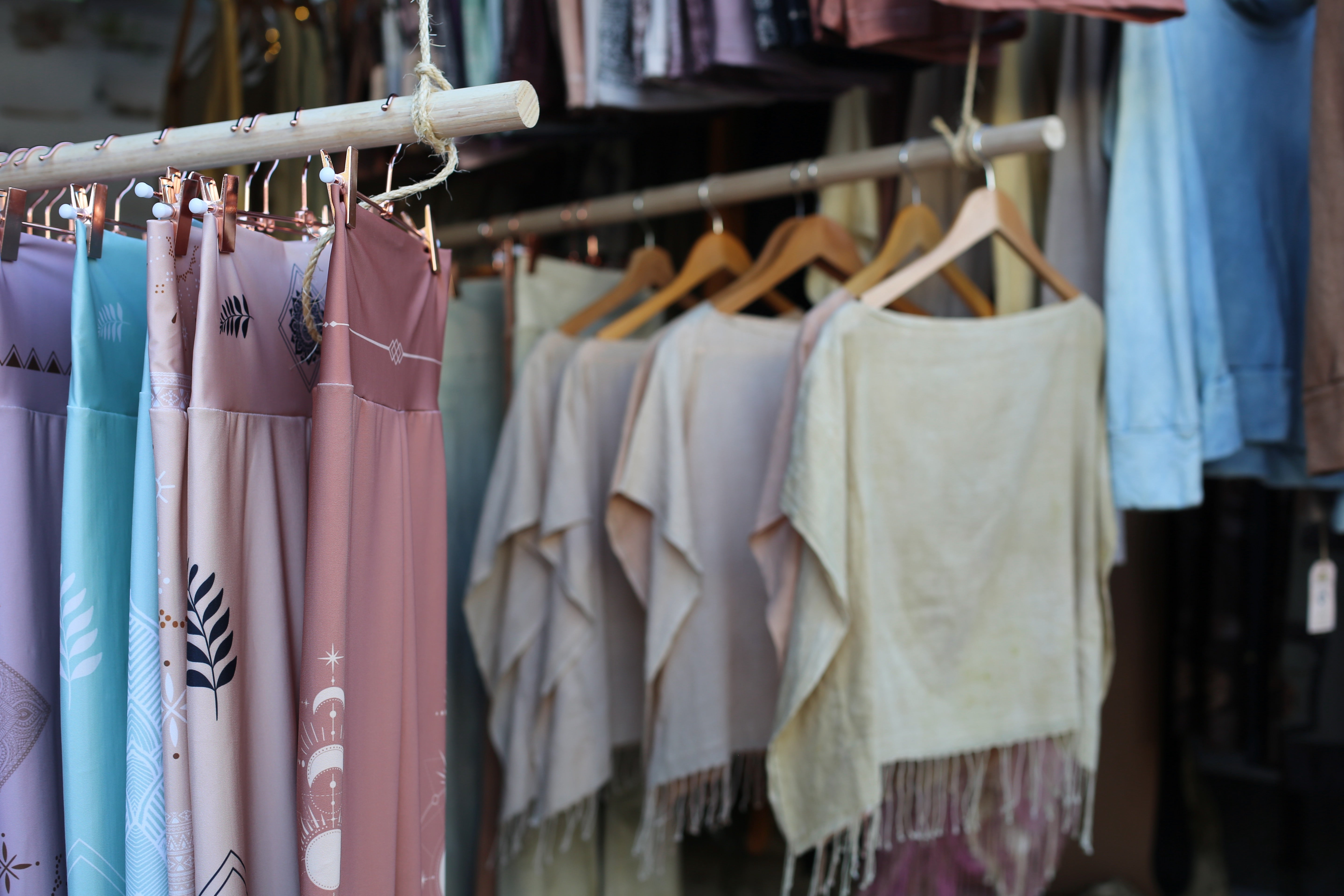 yoga leggings hanging on a bamboo rack with rose gold hangers and hand dyed t shirt poncho tops hanging behind on wooden hangers