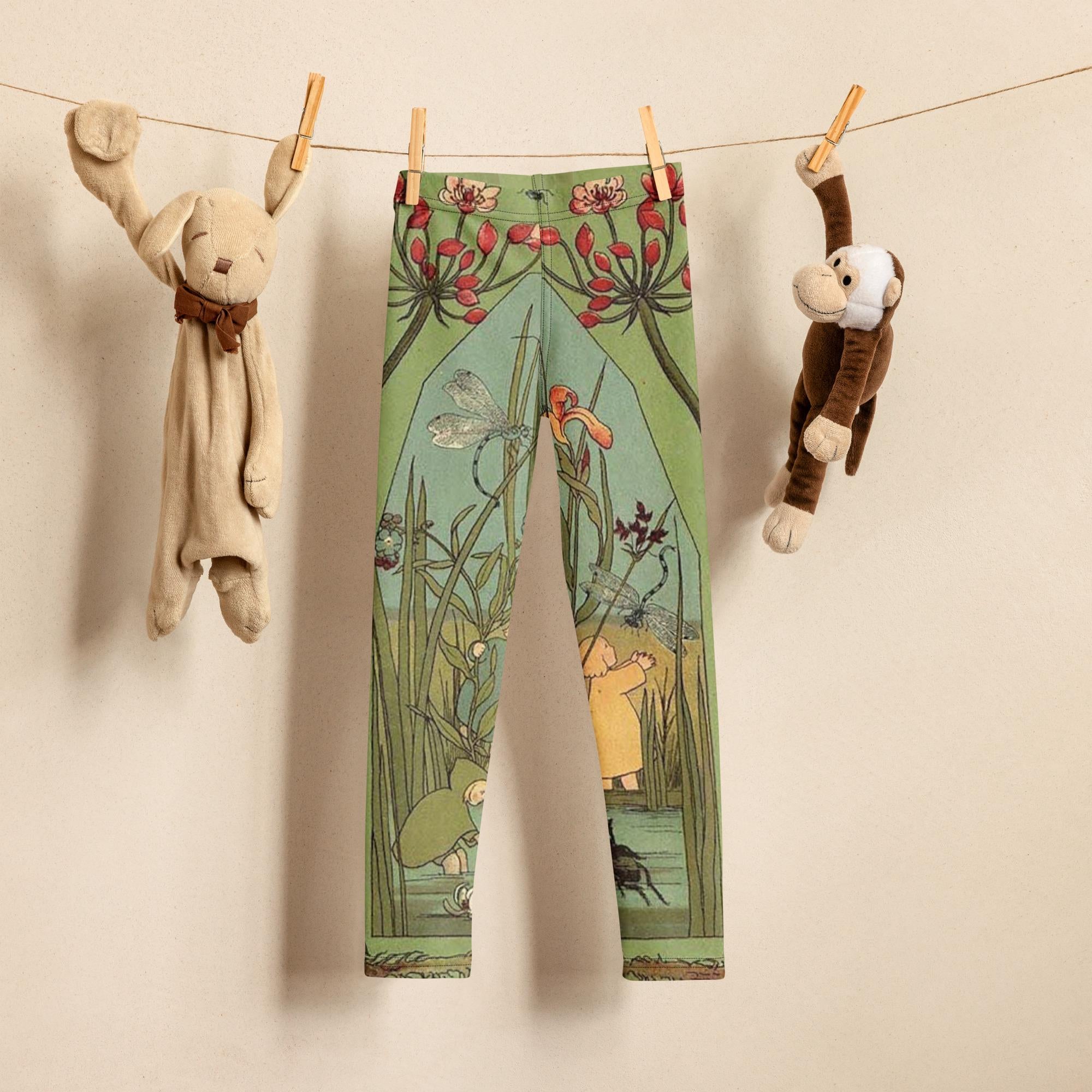 Little girl wearing green and blue illustrated leggings from Elsa beskows the root children. the leggings have images of little flower children in simple clothes and beautiful flowers. they are mostly teal green with some teal blue