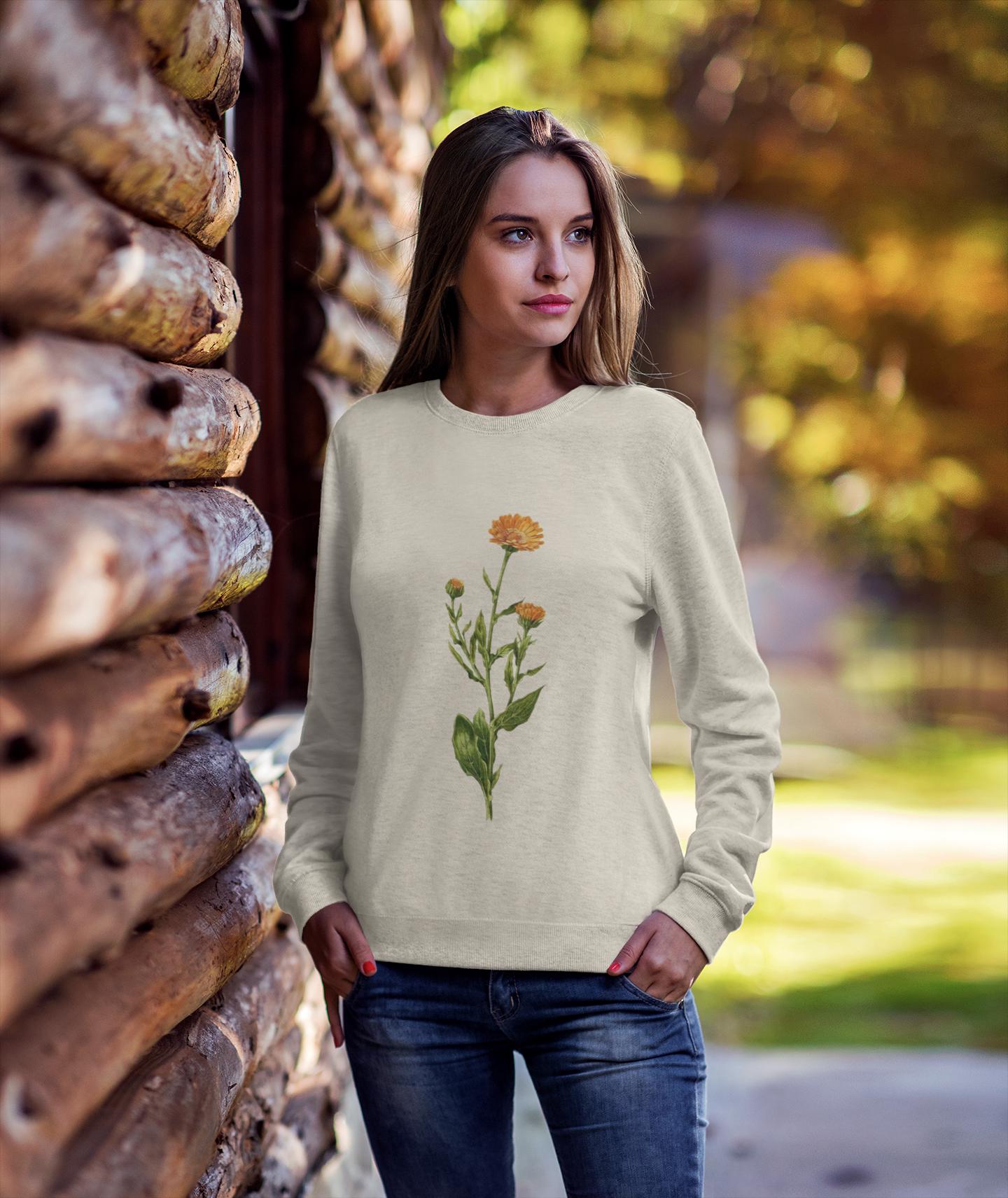 woman swearing a cream colored crewneck sweatshirt with a calendula flower printed on it