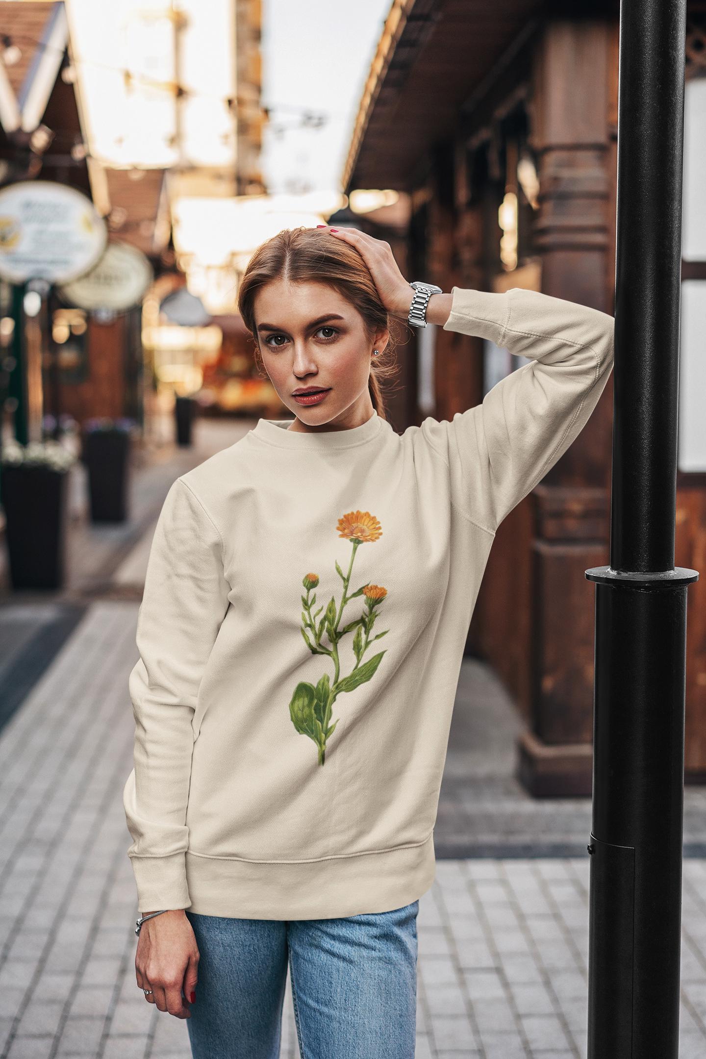 woman swearing a cream colored crewneck sweatshirt with a calendula flower printed on it