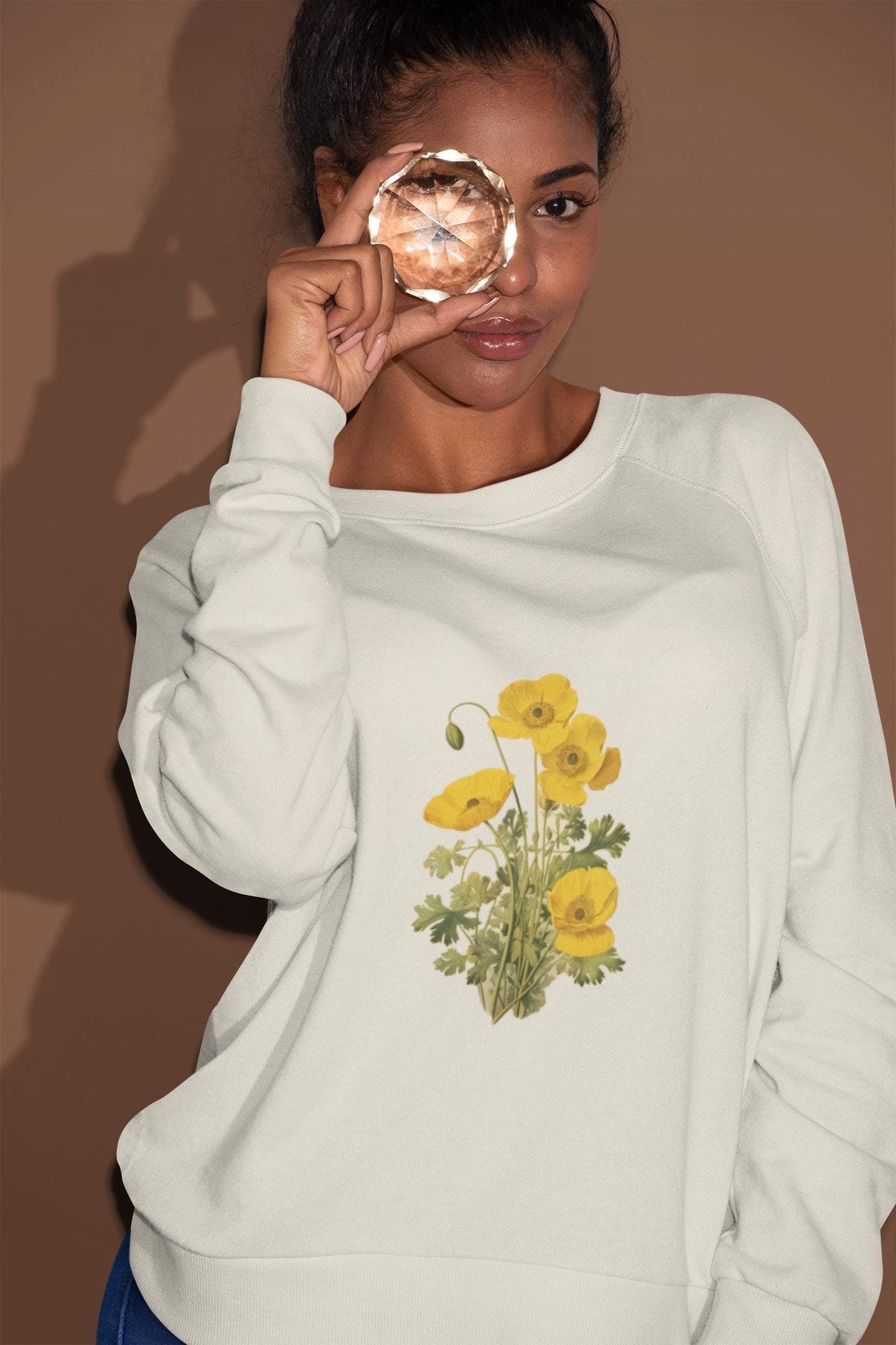 woman wearing a cream colored crewneck sweatshirt with yellow poppies on it