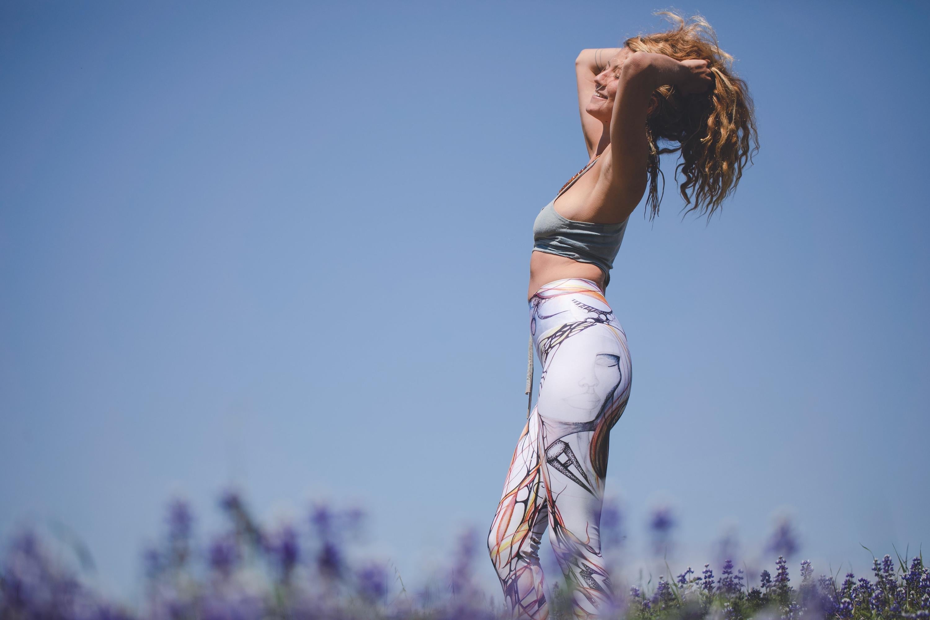 woman with long curly blonde hair blissfully standing in a filed of lavender and sunshine with a clear blue sky