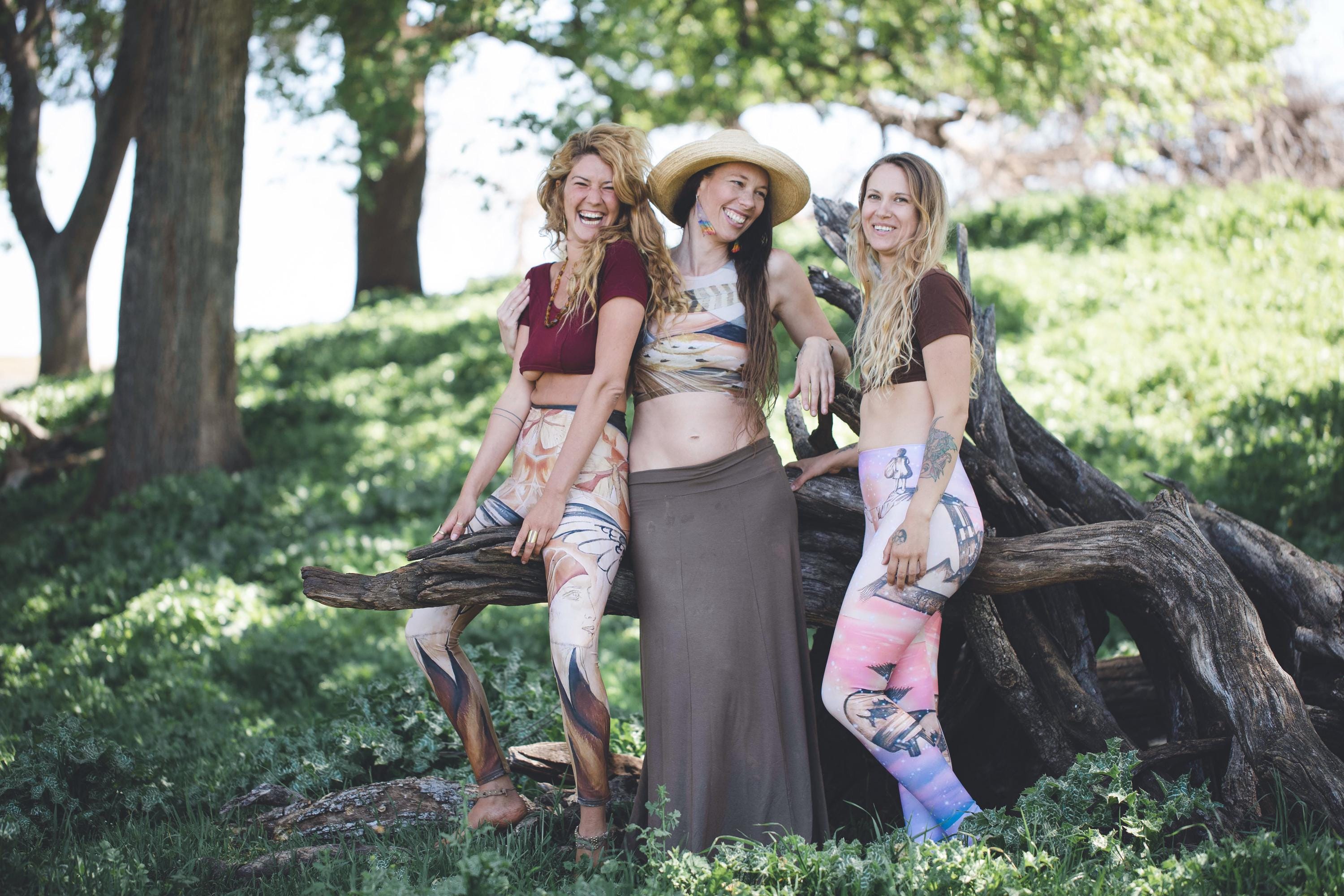 3 women wearing Yoga leggings in shades of pink and blue with a surreal pencil drawing of a little girl printed onto them