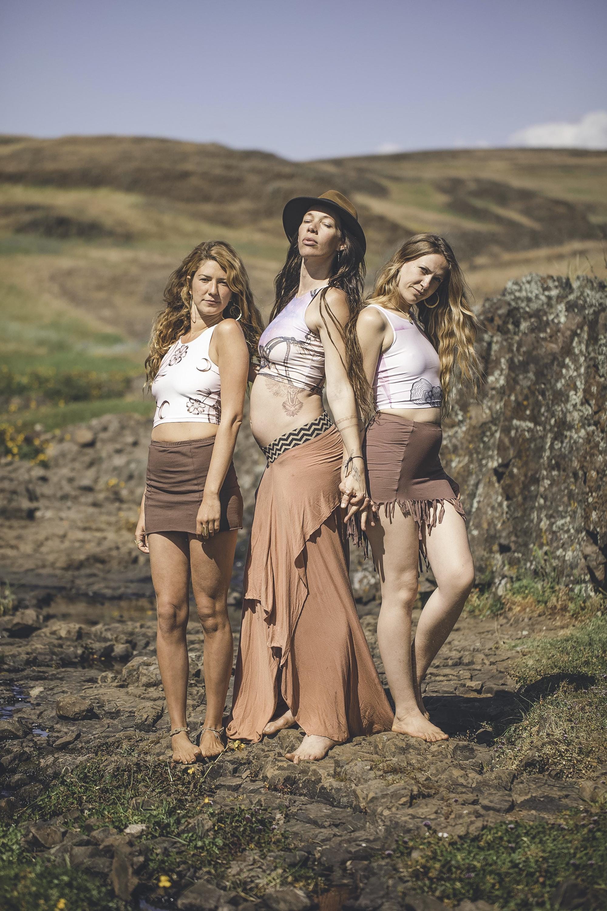 3 women wearing Yoga tops in shades fo cream and white with a black drawing fo a mushroom and accents of pink on it out in valley