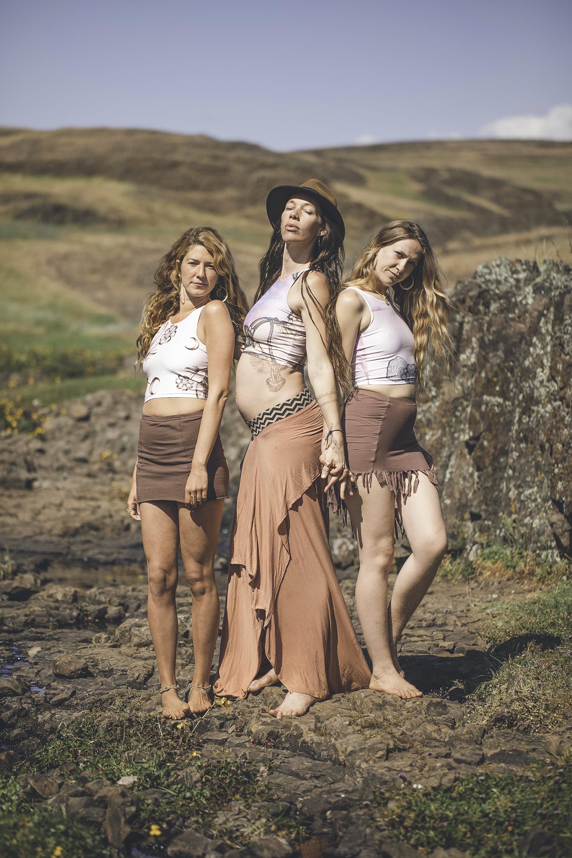 3 women wearing white yoga tank tops with a floral pattern and crescent moons in pink and brown colors.