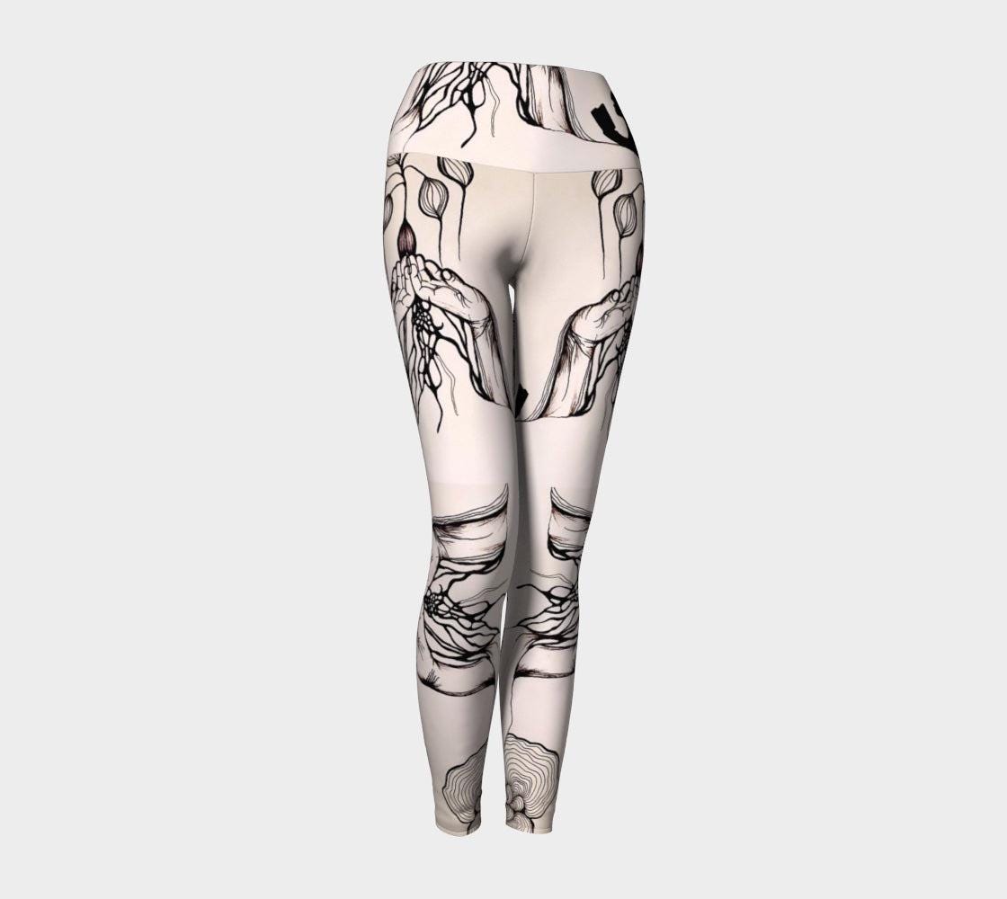 Black and white yoga leggings with designs of hands and plants and subtle hues of pink of them