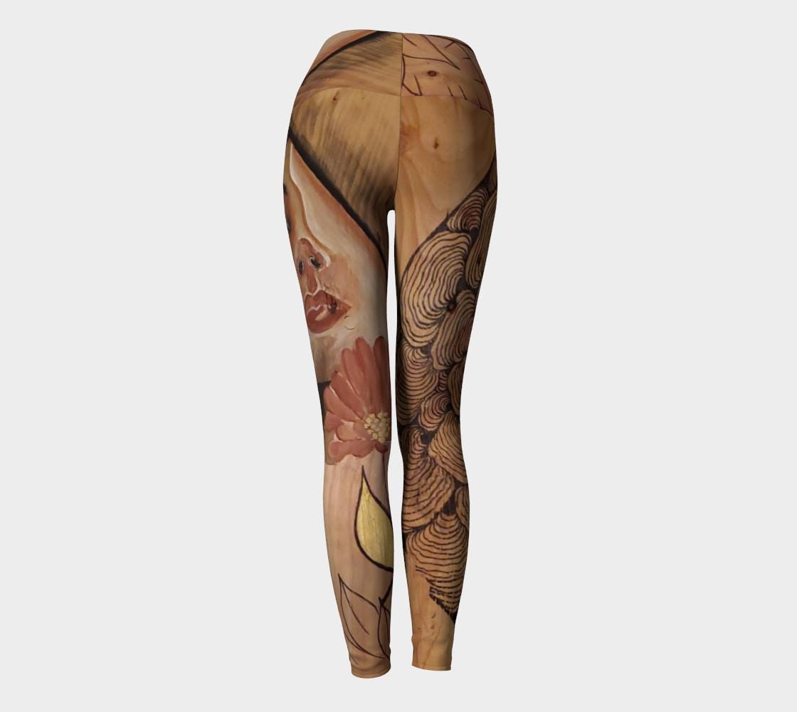 Yoga leggings with a woman face and reishi mushroom black lines painted on reclaimed wood with a gold earring and a red flower