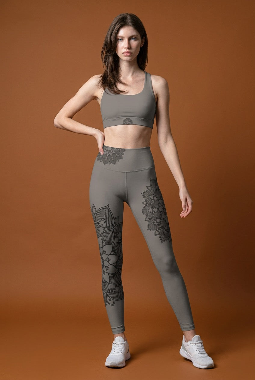 Woman wearing gray athletic leggings with lotus mandala patterns on a brown background
