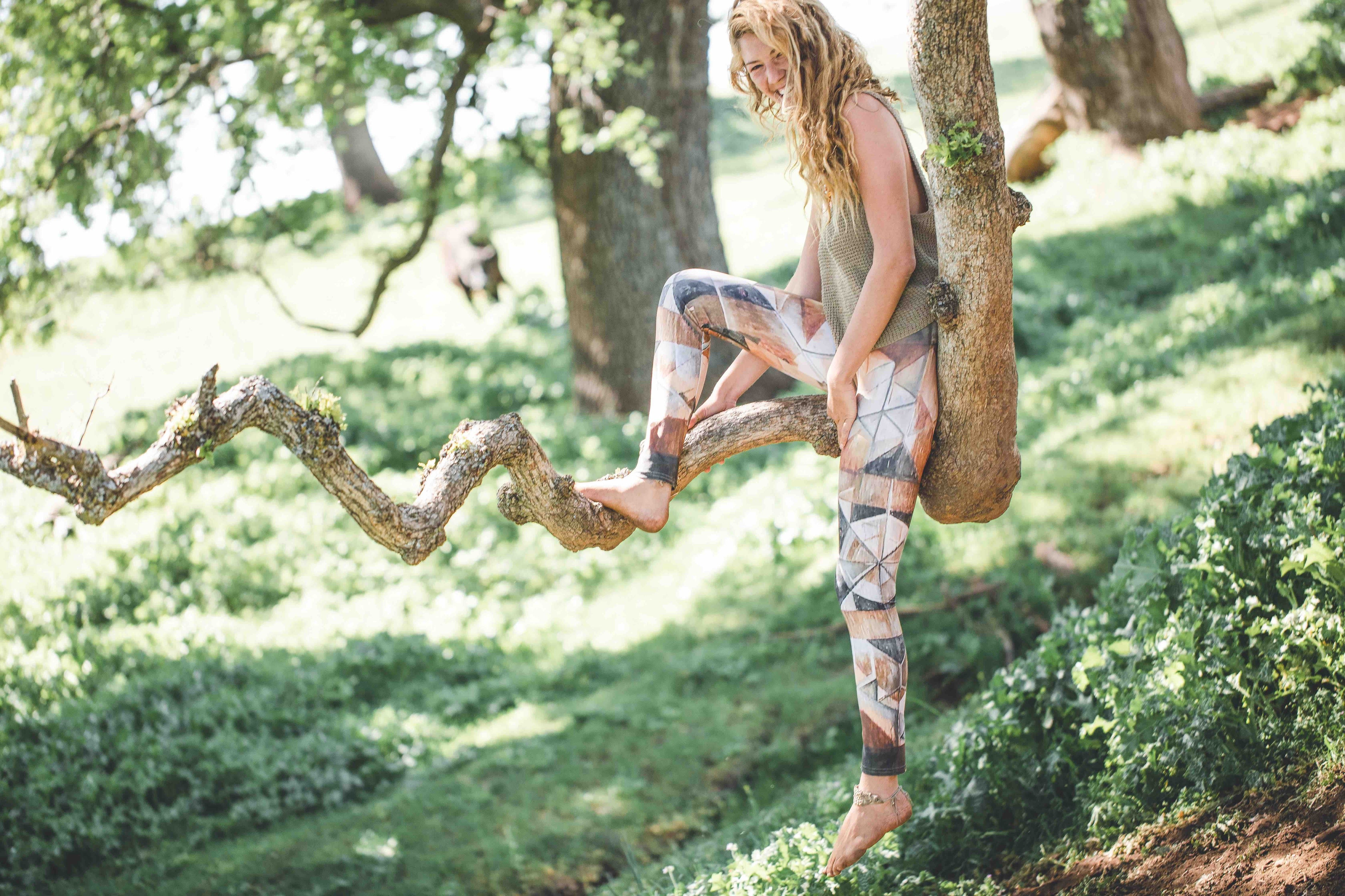 woman in yoga pants in forest sititng on tree