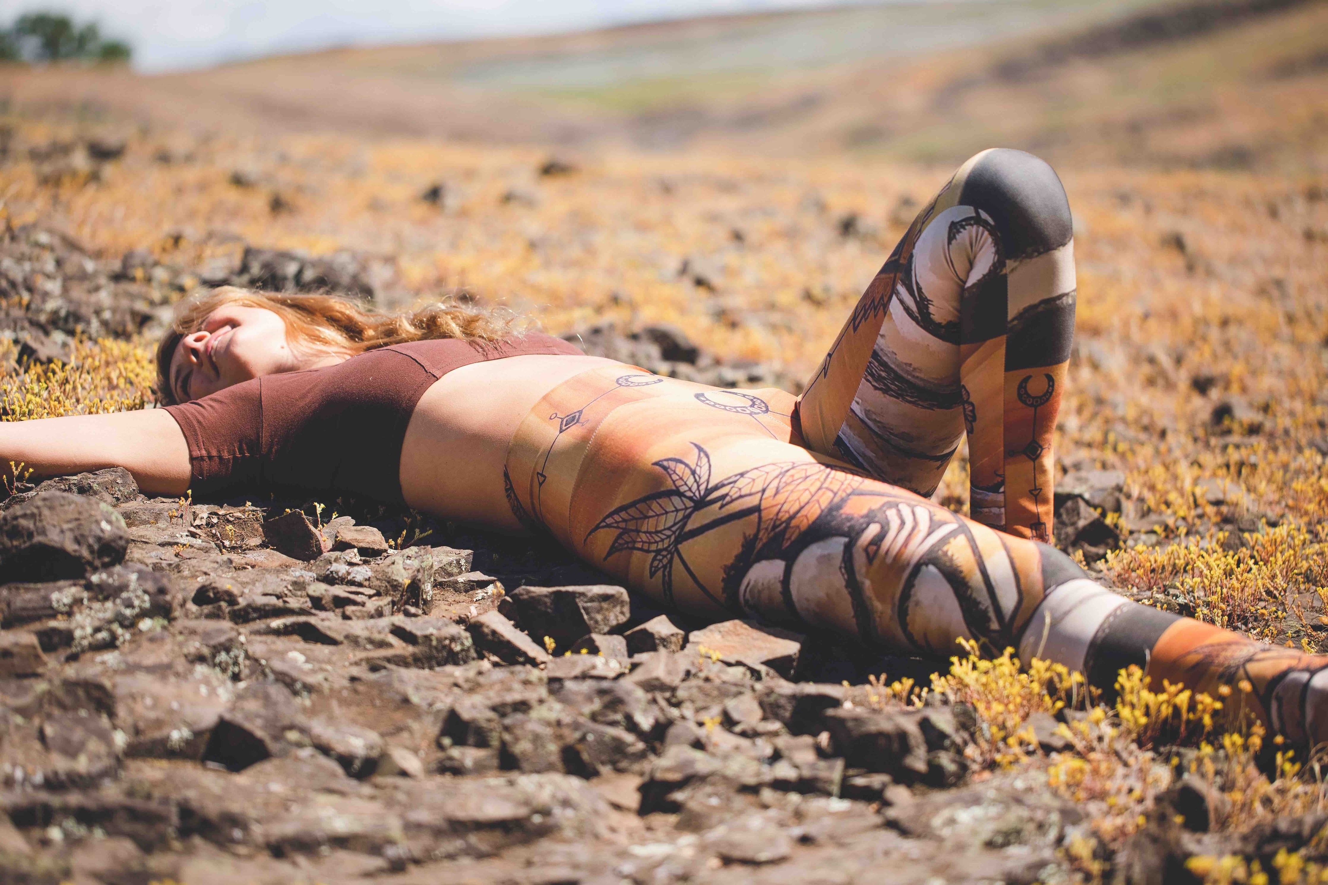 woman in yoga pants in field with rock 